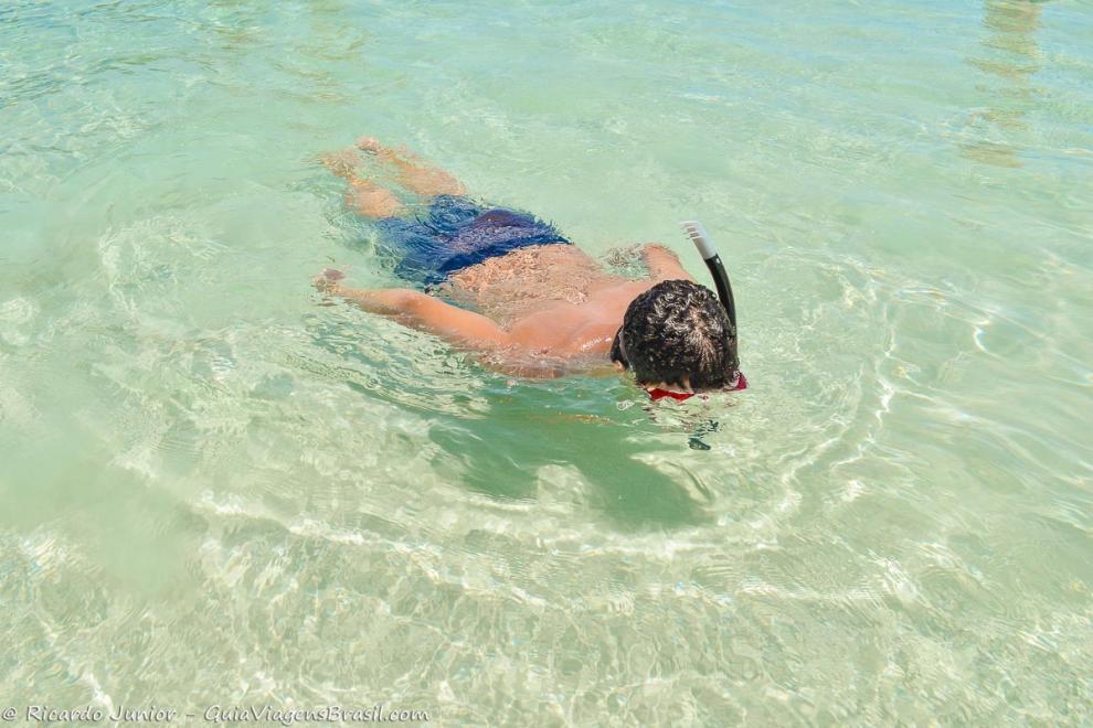 Imagem de um menino mergulhando nas águas claras em Arraial do Cabo.